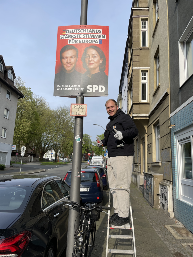 Pascal König neben einem SPD-Wahlkampfplakat.